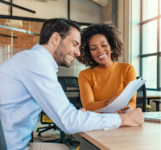 smiling man and woman in office looking a document