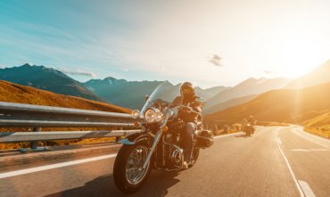 Side front view of two motorcycle riders on the road during sunset