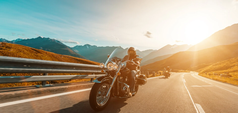 Side front view of two motorcycle riders on the road during sunset