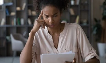Worried young african american woman at paper bills