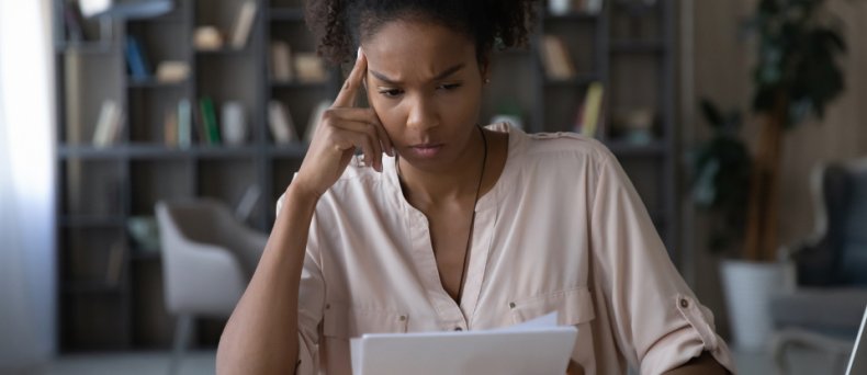 Worried young african american woman at paper bills