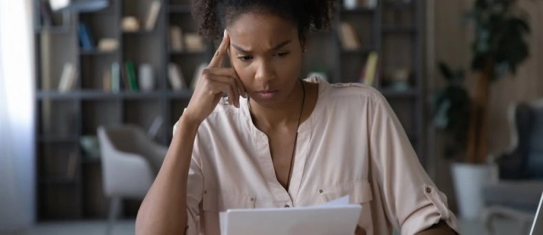 Worried young african american woman at paper bills