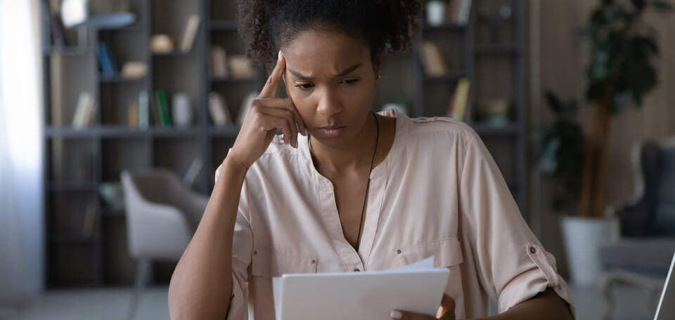 Worried young african american woman at paper bills