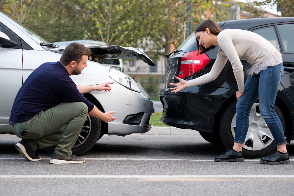 people arguing in front of wrecked cars