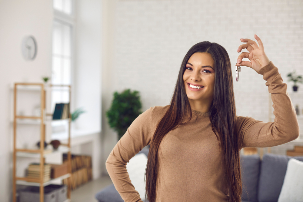 young woman holding up keys to first apartment
