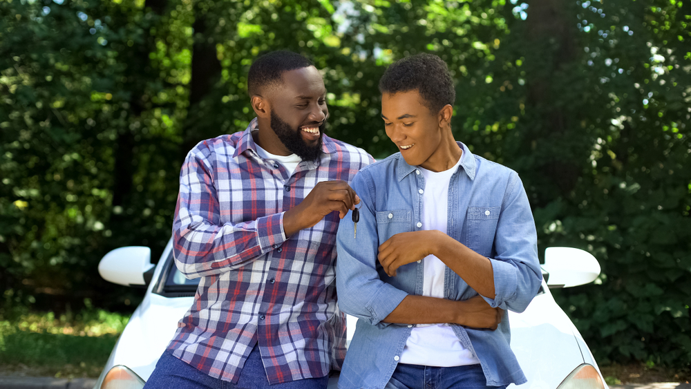 african americna father handing car keys to son