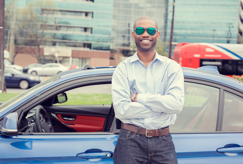 african american man standing outside of car smiling