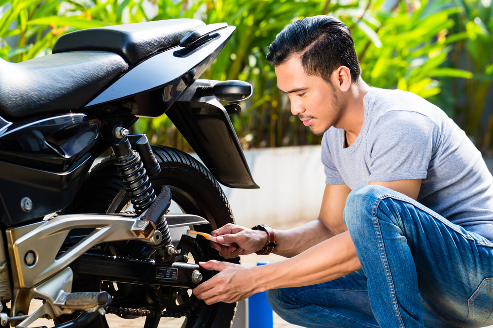 asian man doing maintenance on motorcycle