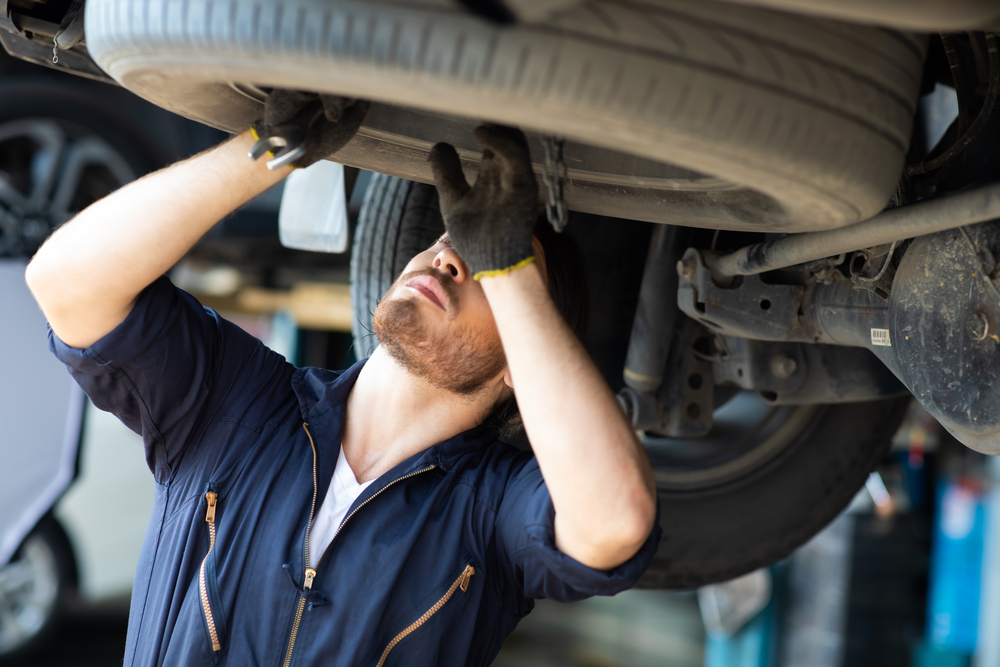 mechanic inspecting tires under car