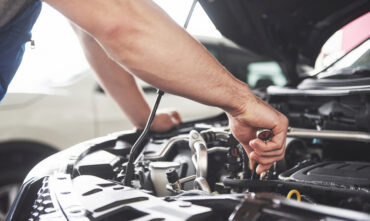 close up of hands doing maintenance under hood of car