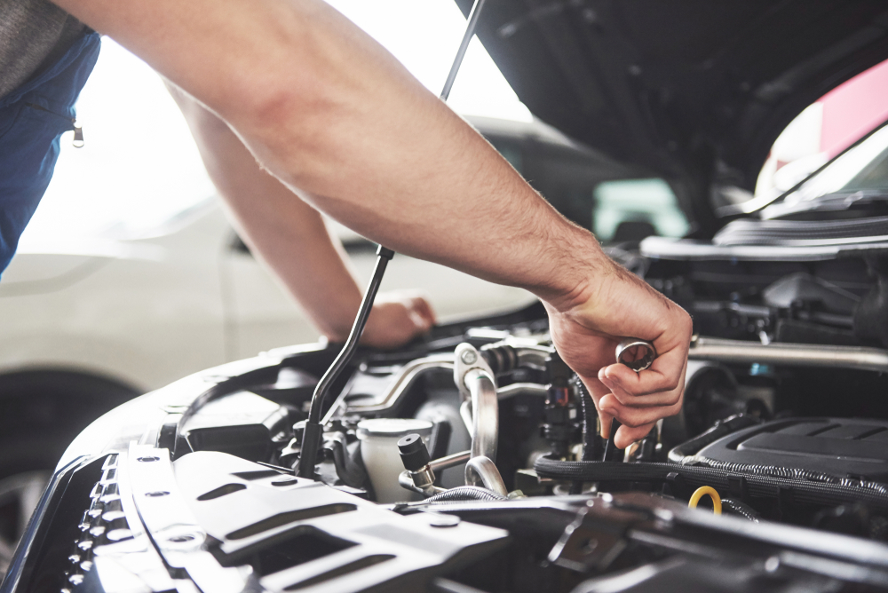 close up of hands doing maintenance under hood of car