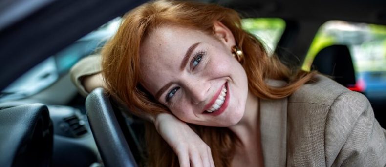 Woman smiling from the driver’s seat, creating a confident everyday driving moment for comprehensive car insurance in Georgia.