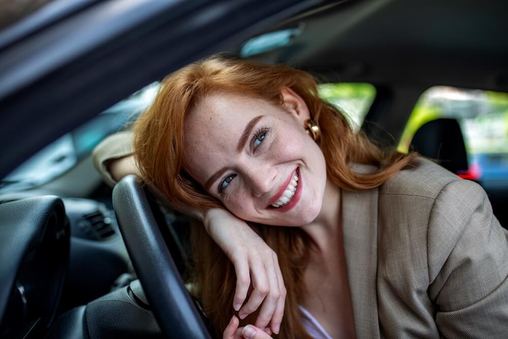 Woman smiling from the driver’s seat, creating a confident everyday driving moment for comprehensive car insurance in Georgia.