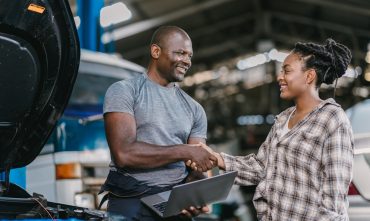 Happy customer dealing hand shaking with mechanic man fix car problem, perform car maintenance for long life of car in Georgia. Satisfied garage car service.