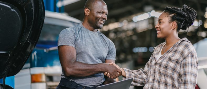 Happy customer dealing hand shaking with mechanic man fix car problem, perform car maintenance for long life of car in Georgia. Satisfied garage car service.
