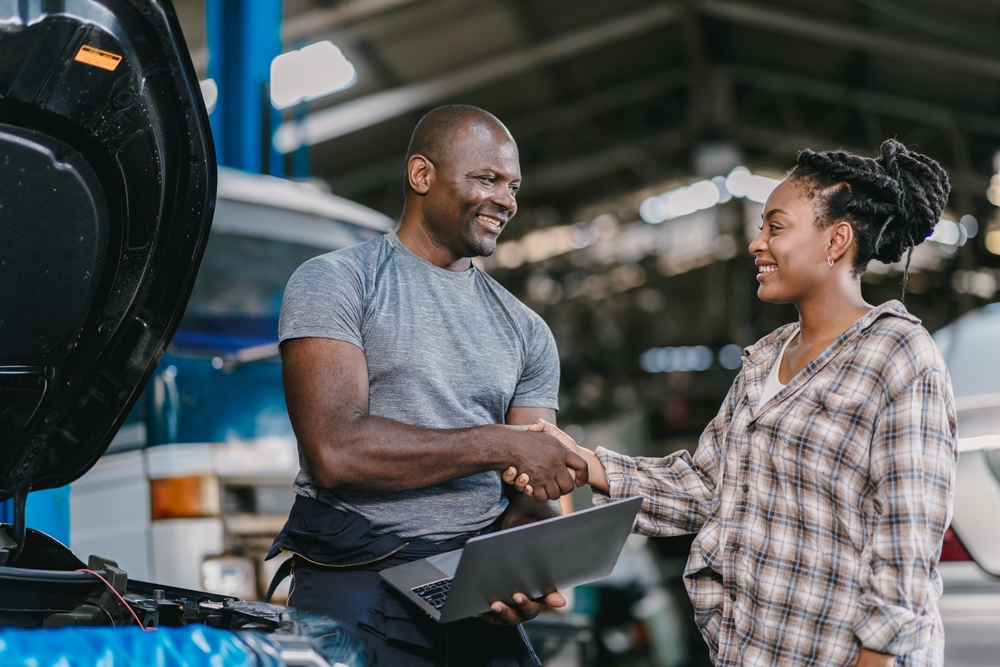 Happy customer dealing hand shaking with mechanic man fix car problem, perform car maintenance for long life of car in Georgia. Satisfied garage car service.