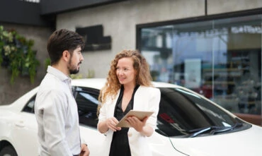Saleswoman shows millennial man a contract for car insurance