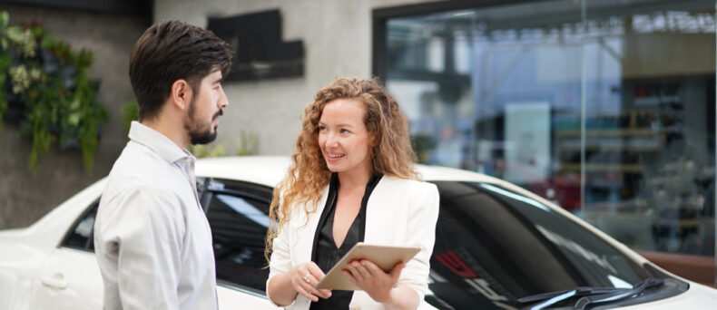 Saleswoman shows millennial man a contract for car insurance