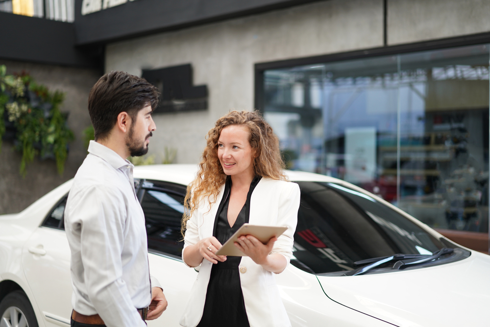 Saleswoman shows millennial man a contract for car insurance