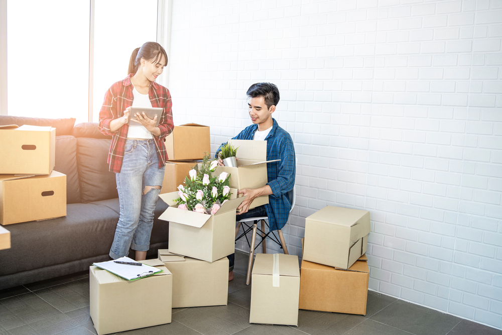 young couple moving with boxes and taking notes of items