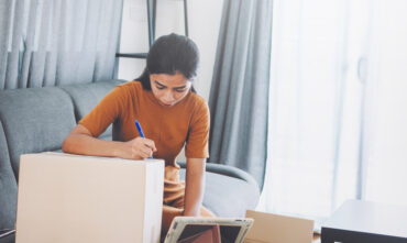 young woman taking notes of moving boxes