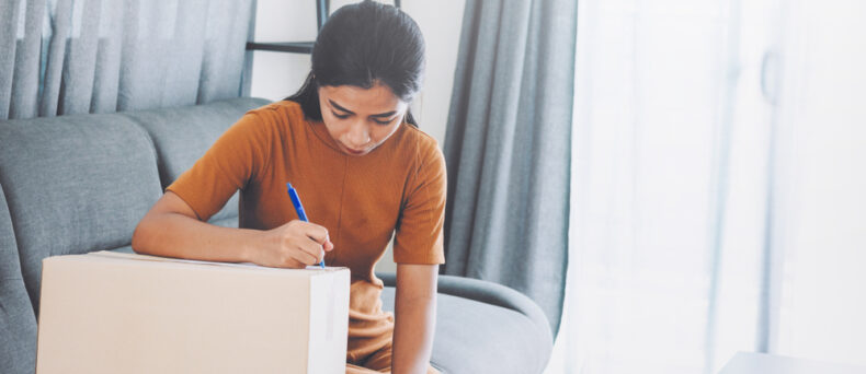 young woman taking notes of moving boxes