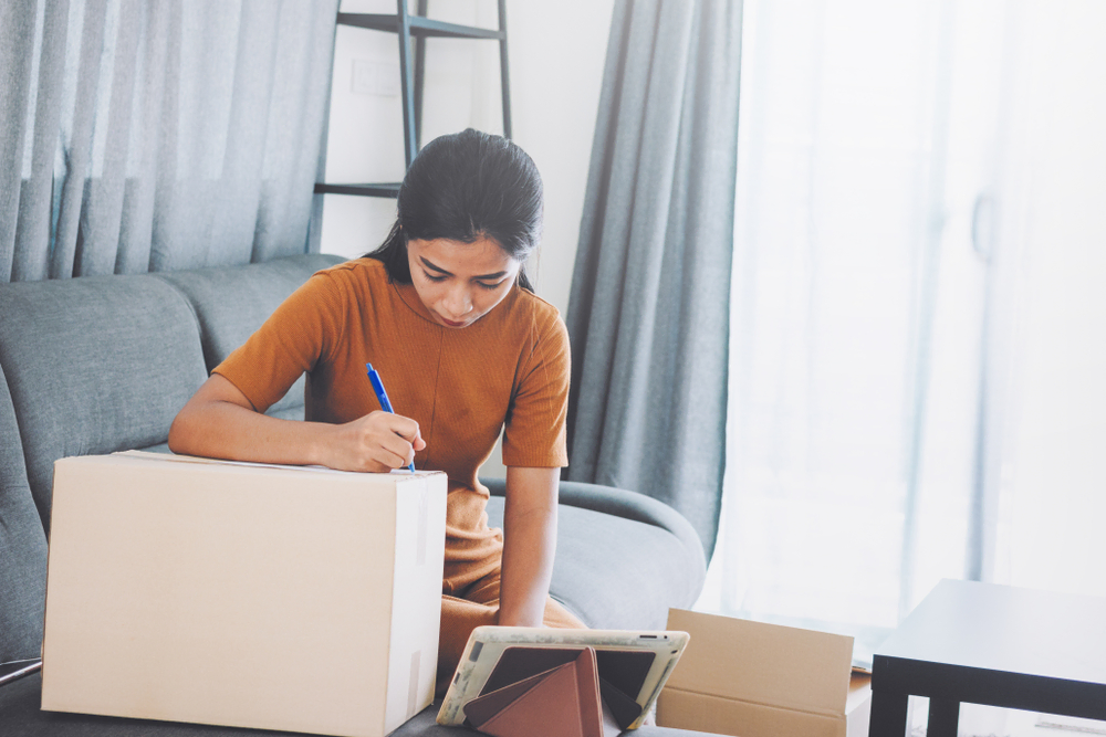 young woman taking notes of moving boxes