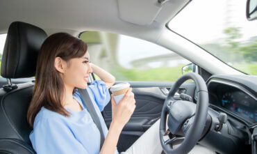 Asian woman in self driving car drinking coffee