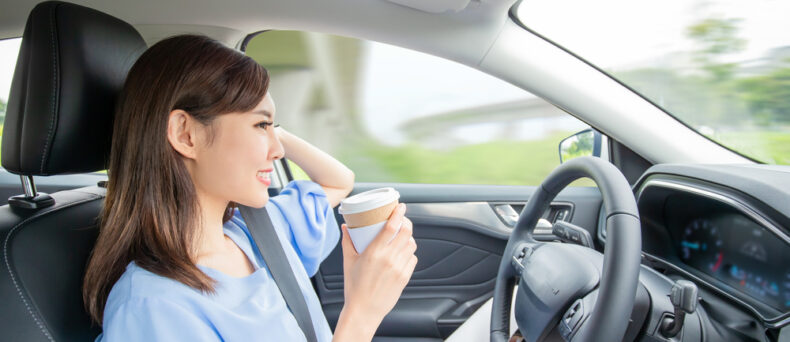 Asian woman in self driving car drinking coffee