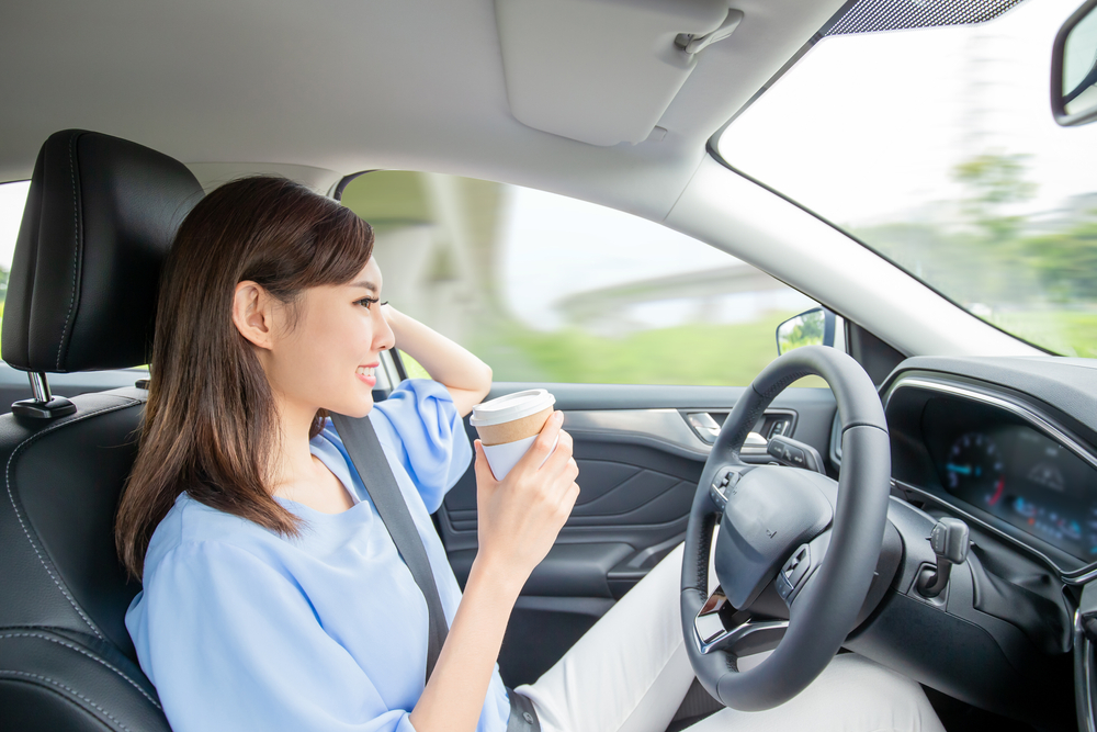 Asian woman in self driving car drinking coffee
