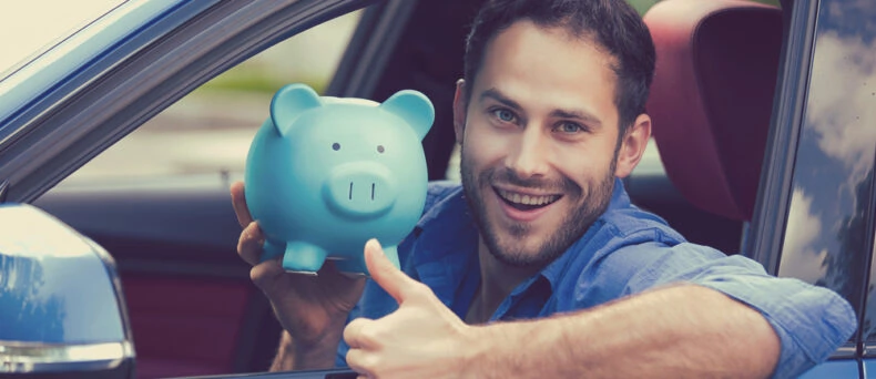 man in driver's seat of car smiling with piggy bank and thumbs up