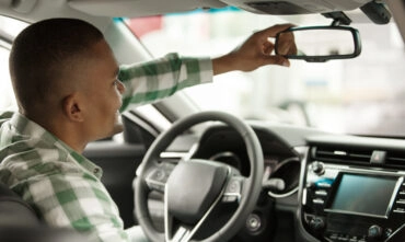 driver adjusting rear view mirror in car