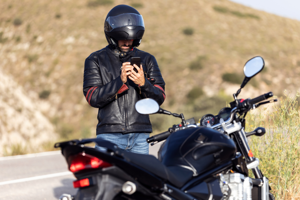 motorcyclist standing by bike on phone