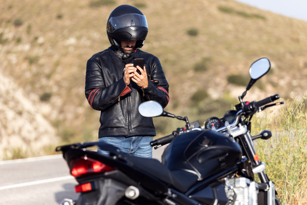 motorcyclist standing by bike on phone