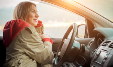 woman in coat behind wheel of car