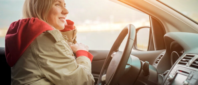 woman in coat behind wheel of car