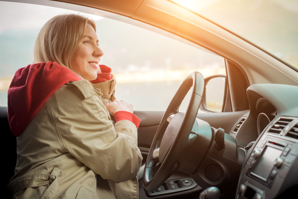 woman in coat behind wheel of car