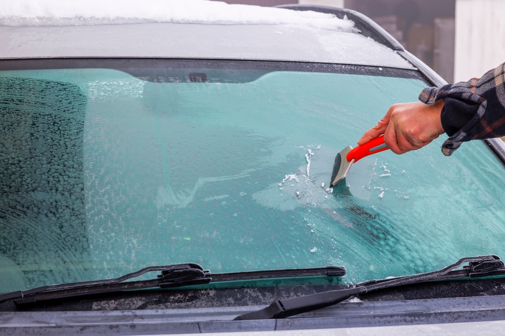 person scraping ice off car windshield