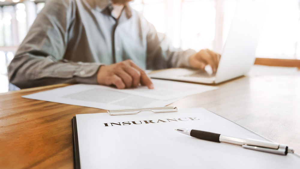 person sitting in front of insurance document at desk