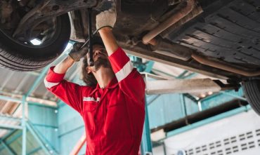 Mechanic inspecting a vehicle underside, highlighting how to spot common car repair scams before approving repairs.