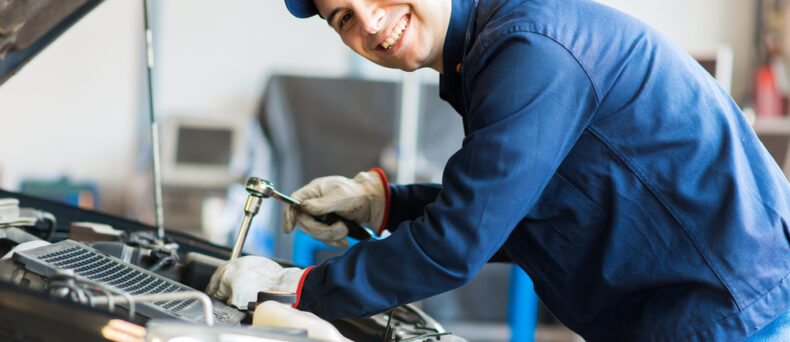 Smiling mechanic works under the hood