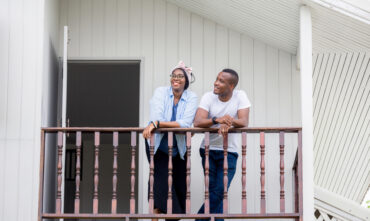 African American couple thinks about getting renters insurance while standing on the balcony of their apartment