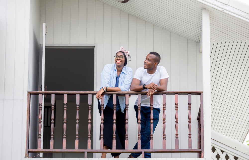 African American couple thinks about getting renters insurance while standing on the balcony of their apartment