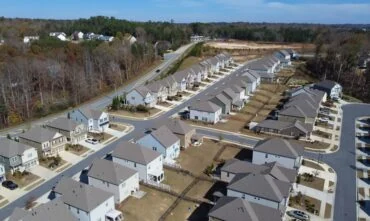 Aerial view of a row of HOA master development of new two-story buildings and construction side in the background Flores Subdivision, suburbs Atlanta, Georgia, USA. Front garage houses