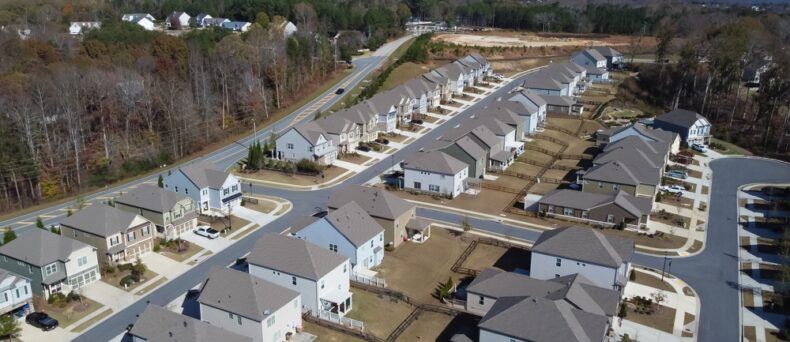 Aerial view of a row of HOA master development of new two-story buildings and construction side in the background Flores Subdivision, suburbs Atlanta, Georgia, USA. Front garage houses