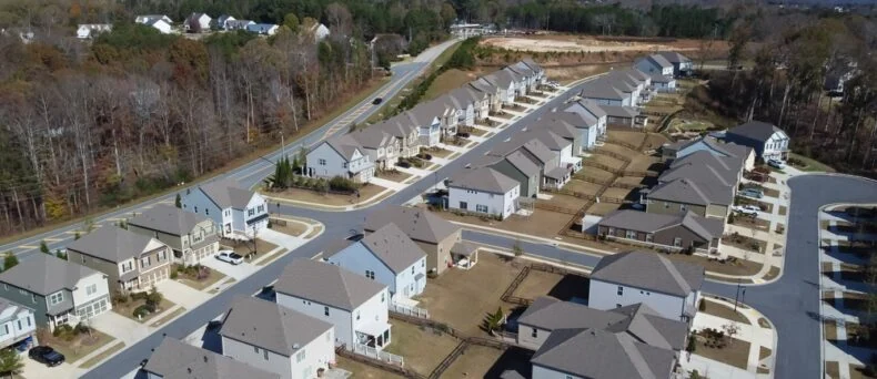 Aerial view of a row of HOA master development of new two-story buildings and construction side in the background Flores Subdivision, suburbs Atlanta, Georgia, USA. Front garage houses