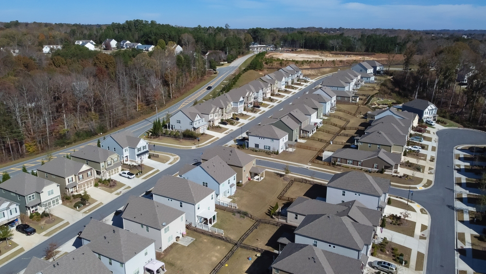 Aerial view of a row of HOA master development of new two-story buildings and construction side in the background Flores Subdivision, suburbs Atlanta, Georgia, USA. Front garage houses