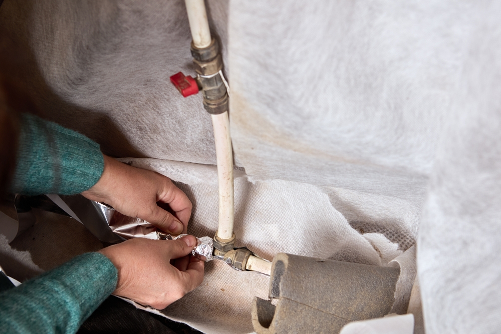 hands wrap pipes before a freeze