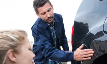 Man and woman examine a dent in a car