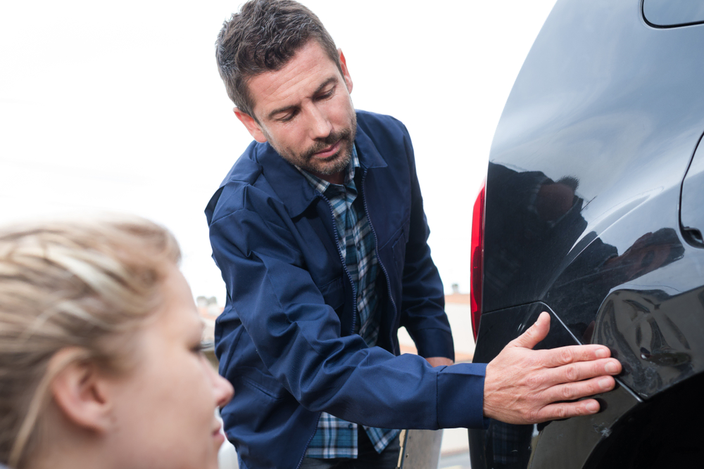 Man and woman examine a dent in a car